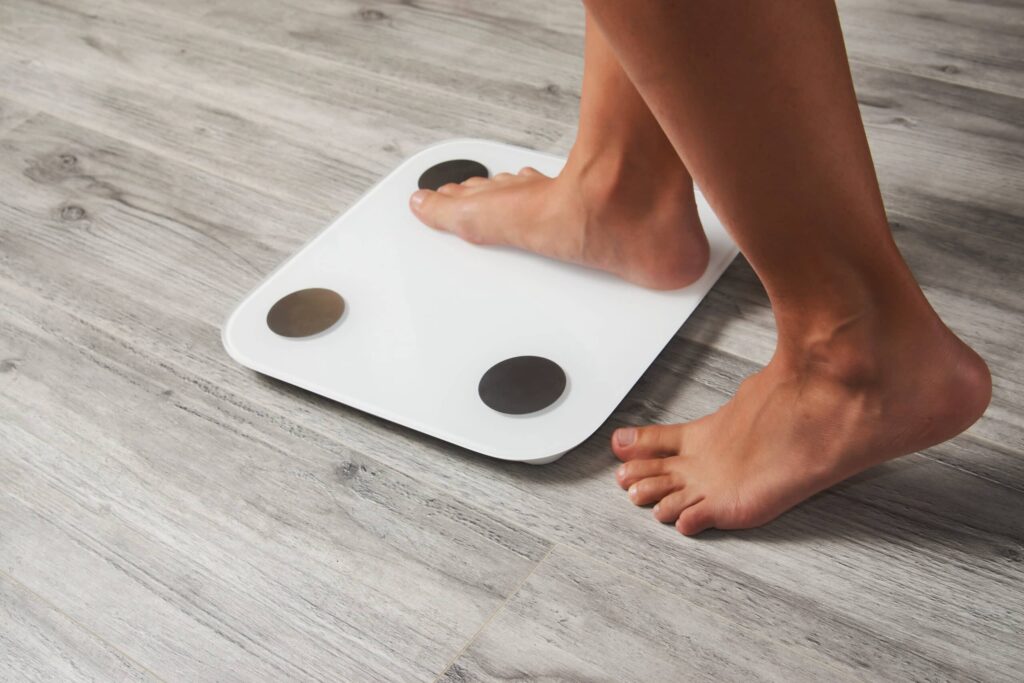 Woman stepping on scale to measure weight loss after cold plunge
