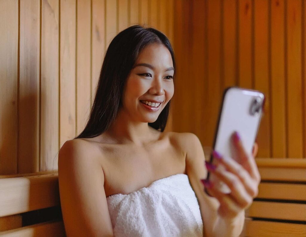 Woman using phone in sauna to Facetime friend
